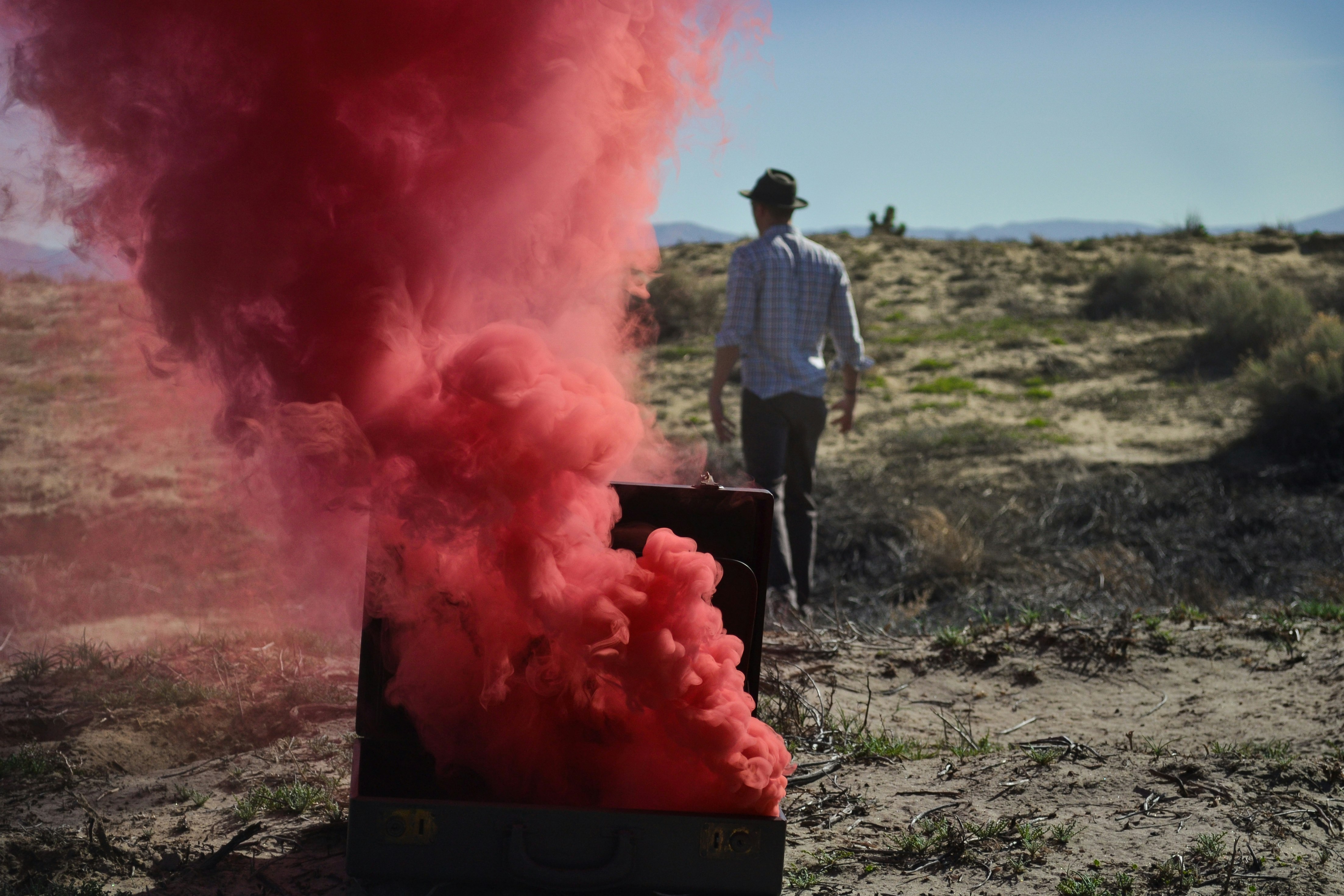 red smoke bomb on chest near man wearing black cap